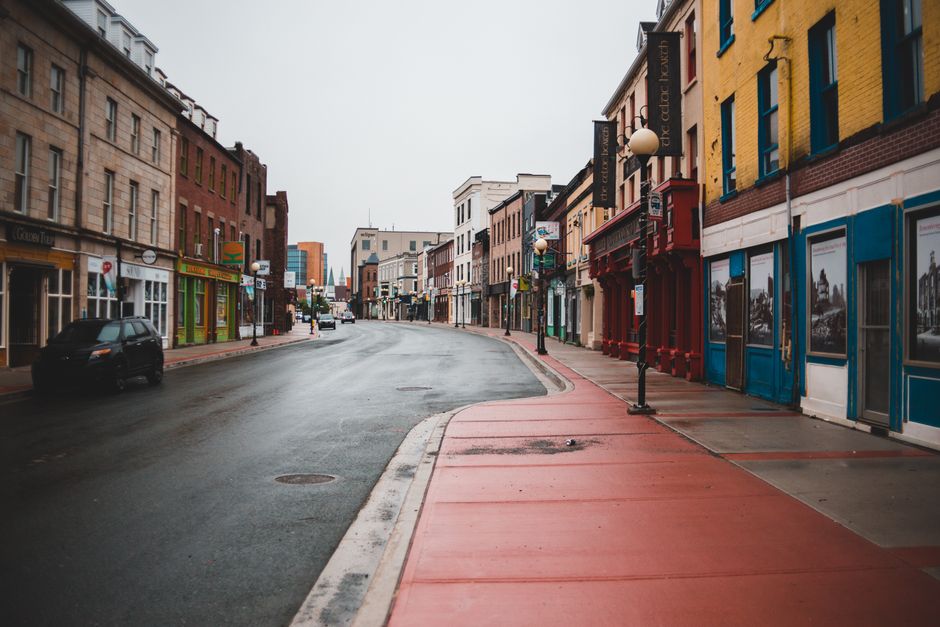 Asphalt roadway and sidewalk between aged stone building exteriors with bright walls in town